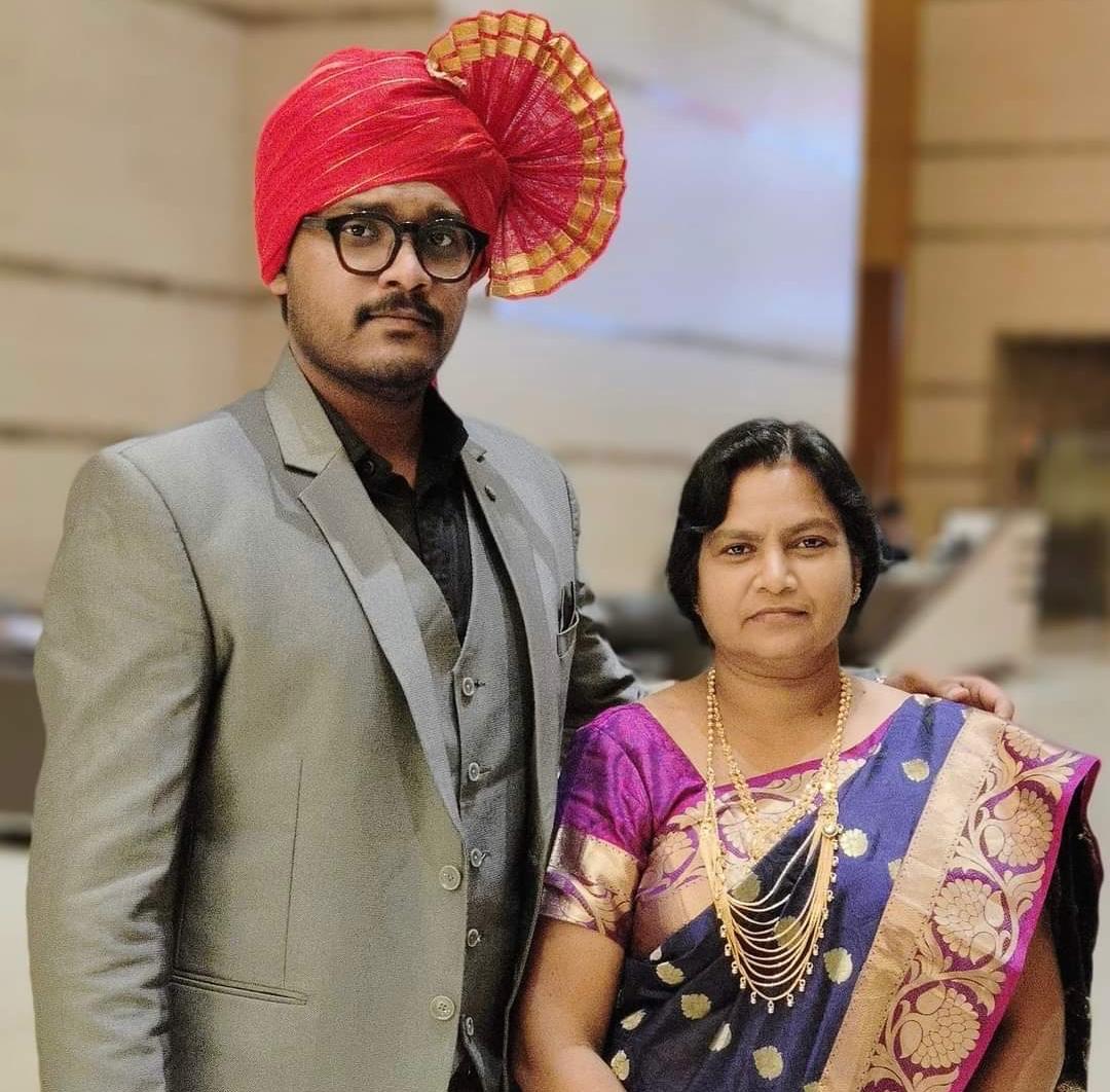 A confident man in a grey suit and bright red turban stands beside a woman in a royal purple and gold saree, both posing with grace. Symbolizes our new branding partner’s philosophy of combining tradition, emotion, and contemporary branding vision.