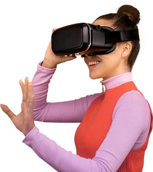 A woman in a pink full-sleeve top and orange sweater wearing a VR headset, reaching forward to interact with a virtual environment — representing New Branding Partner’s focus on immersive digital experiences.
