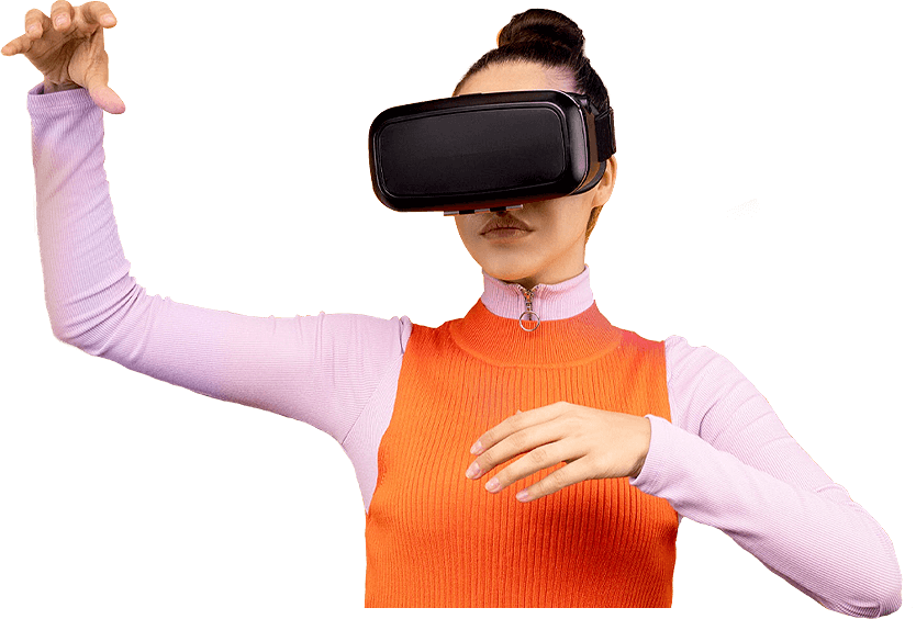 A woman in a pink full-sleeve top and orange sweater wearing a VR headset, reaching forward to interact with a virtual environment — representing New Branding Partner’s focus on immersive digital experiences.